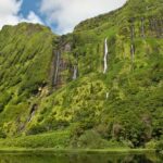 Lush green cliffs of Flores Island with multiple cascading waterfalls, reflecting the island's untouched natural beauty. The verdant landscape is a key highlight in Flores travel guide.