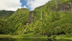 Lush green cliffs of Flores Island with multiple cascading waterfalls, reflecting the island's untouched natural beauty. The verdant landscape is a key highlight in Flores travel guide.