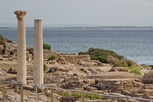 Ancient ruins of Tharros in Sardinia with two standing columns overlooking the Mediterranean Sea, showcasing the historical and scenic beauty highlighted in this Sardinia travel guide.