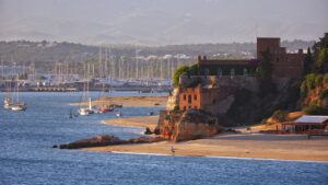 View of the ancient fort of Santa Catarina in Portimão, Portugal, overlooking a sandy beach and a marina filled with sailboats.