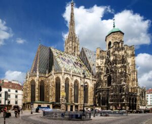 St. Stephen's Cathedral in Vienna, featuring its colorful tiled roof and towering spires under a bright blue sky.