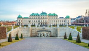 The stunning Baroque architecture of the Belvedere Palace in Vienna, Austria, with its well-manicured gardens and ornate fountains in the foreground.